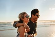 Ein lächelndes Paar am Strand, beide tragen eine Sonnenbrille. Ein lächelndes Paar am Strand, beide tragen eine Sonnenbrille.